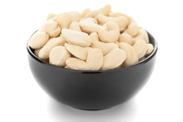 Close-up Organic dry fruit cashew nut (Anacardium occidentale)  in black ceramic  bowl on white background