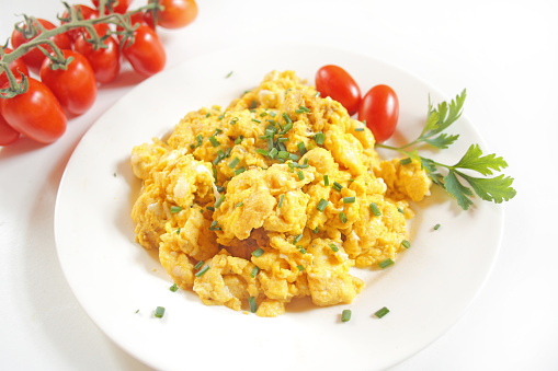 Scrambled eggs and cherry tomatoes on white background