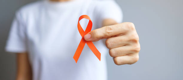 hand halten orange ribbon für leukämie, nierenkrebs tag, welt multiple sklerose, crps, selbstverletzung bewusstsein monat. gesundheits- und wortkrebs-tageskonzept - sclerosis stock-fotos und bilder