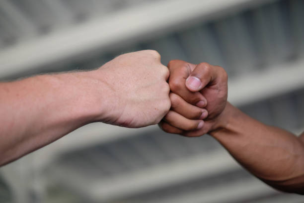 Multi-Ethnic Friend Doing Fist Bump to Celebrate Success Close-up shot of two unrecognizable hands with different skin tone color doing fist bump to celebrate their successful anti-racism event. There's light and dark skin male hands. racial equality photos stock pictures, royalty-free photos & images