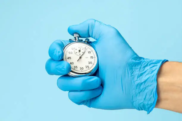 Doctor in glove holds stopwatch in his hand. Fast medical assistance and consultation concept.