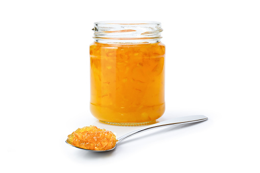 Orange marmalade jam in glass jar and spoon isolated on white background.