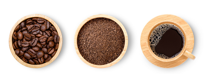 Roasted coffee beans, coffee powder (ground coffee) in wooden bowl and wooden cup of hot black coffee isolated on white background. Top view. Flat lay.