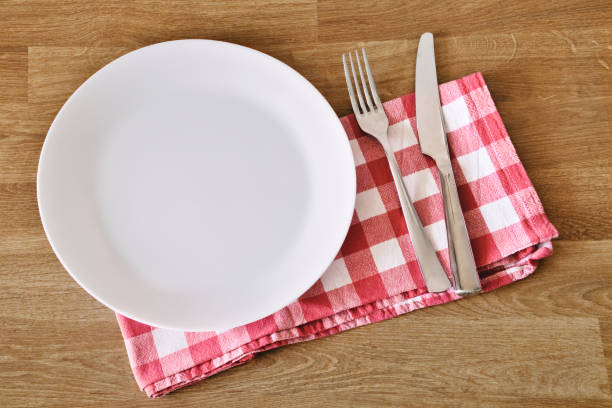 istock Empty white plate, fork, knife and towel over wooden table background. Copy space and place for meal. 1333158233