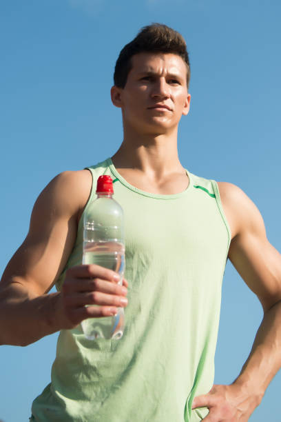 istock Man with water bottle in muscular hands 1333158247
