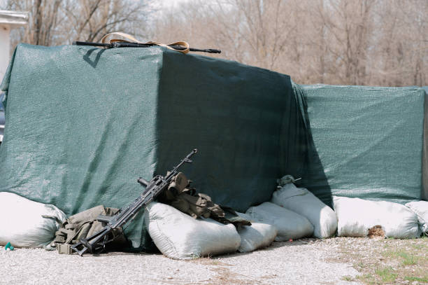 istock Weapons and equipment for playing airsoft lying on the ground and defensive structures 1333158626