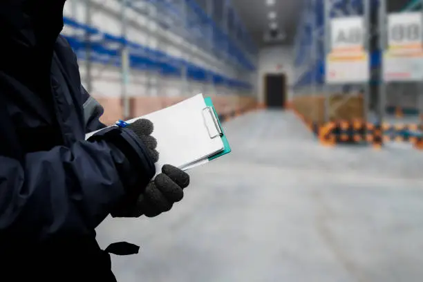 Closeup shooting hand of worker with clipboard checking goods in freezing room or warehouse