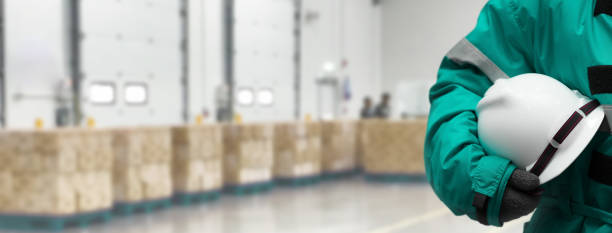 istock Safety Officer holding hardhat  for dangerous accident protection in warehouse during work. Cold room storage and freezing warehouse. Banners with copy space. 1333158660