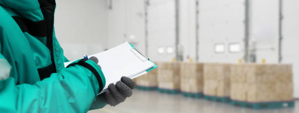 Hand of worker with clipboard checking goods in freezing room or warehouse. Export-Import Logistics system concept. Banners with copy space Hand of worker with clipboard checking goods in freezing room or warehouse. Export-Import Logistics system concept. Banners with copy space cold storage stock pictures, royalty-free photos & images