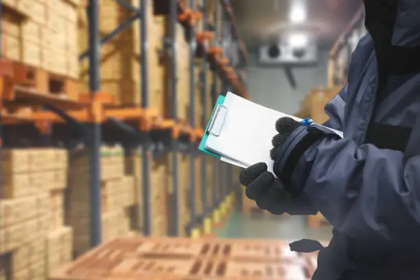 Closeup shooting hand of QC. worker checking goods on delivery in the cold room warehouse., Logistics food and beverage in cold storage concept