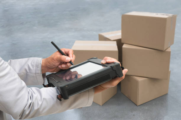 Closeup shooting hand of QC. worker with Rugged computers tablet and Bluetooth barcode scanner checking for logistics, Goods package boxes in warehouse. stock photo