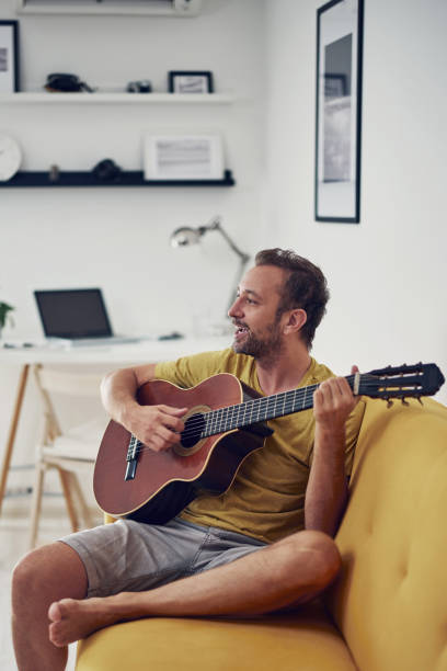 istock Man playing acoustic guitar at home. 1333160443