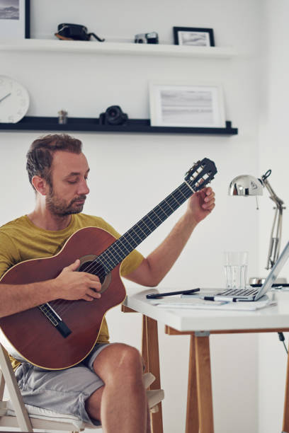 istock Man playing acoustic guitar at home. 1333160606