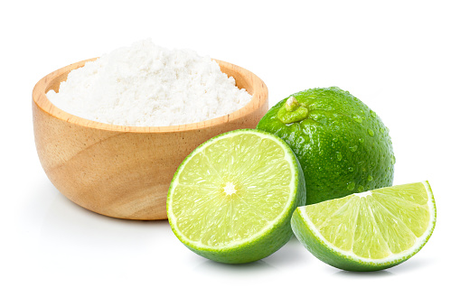 Lime powder in wooden bowl and fresh limes fruit isolated on white background.