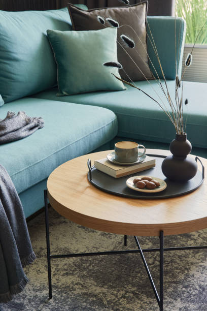 Stylish composition of modern living room interior in small apartment. Eucalyptus sofa, wooden coffee table and personal accessories. Panorama windows with a big city view on. Creative wall. Details. Template. elegante composición del interior de la sala de estar moderna en un pequeño apartamento. sofá de eucalipto, mesa de centro de madera y accesorios personales. ventanas panorámicas con una gran vista de la ciudad en. muro creativo. detalles. plantilla.