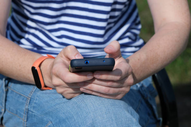istock Person is using smart phone while sitting on the park bench 1333162593