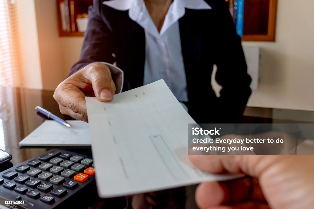 hand giving blank checkbook, Paycheck concepts. Cropped image of business woman hand giving blank checkbook to another. Paycheck and payroll concept. Check - Financial Item Stock Photo