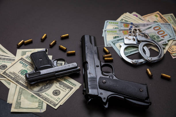 istock Pistol handcuffs and American dollar banknotes on black background. 1333163747