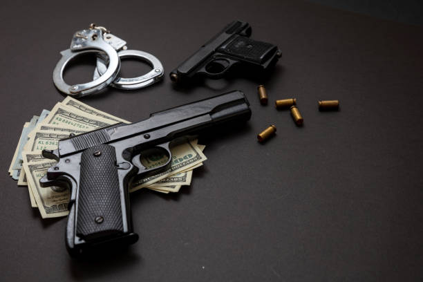 istock Pistol handcuffs and American dollar banknotes on black background. 1333163749