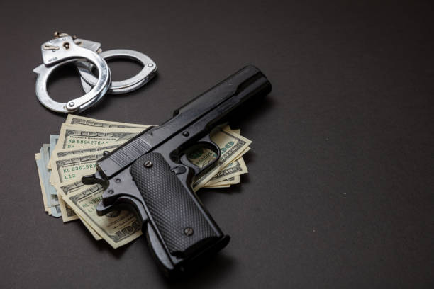 istock Pistol handcuffs and American dollar banknotes on black background. 1333163750