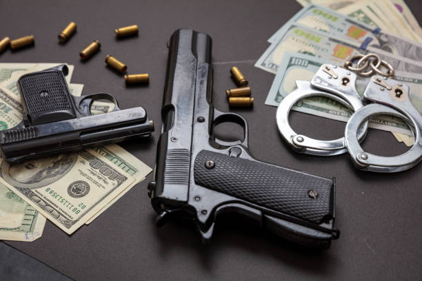 istock Pistol handcuffs and American dollar banknotes on black background. 1333163751