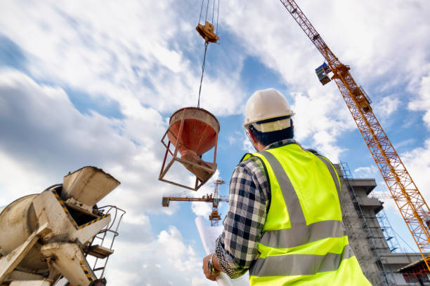 istock Engineering Consulting people on construction site holding blueprint in his hand. Concrete casting in construction site and control workflow of new building. 1333165146
