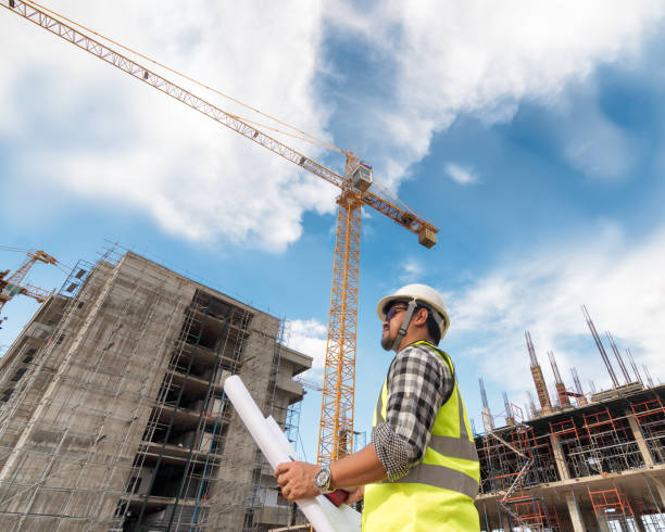istock Engineering Consulting People on construction site holding blueprint in his hand. Building inspector. Construction site check drawing and business workflow of new building 1333165166