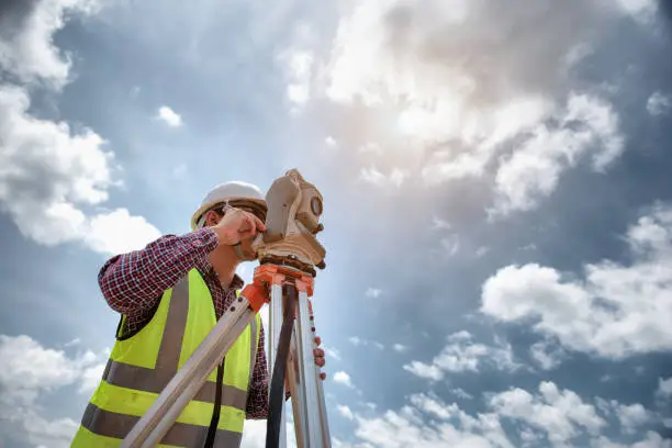 Surveyor Engineering. Surveyor using telescope at construction site, Surveying for making contour plans are a graphical representation of the lay of the land before startup construction work.