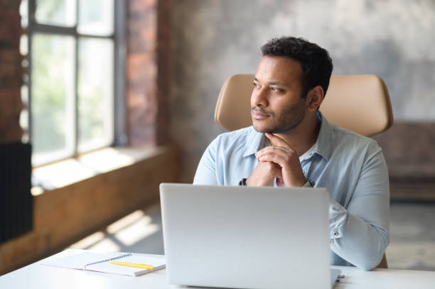 Serious concentrated clever indian freelancer guy using laptop for searching