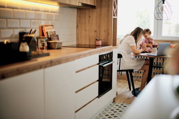istock Stay at mother home sitting in kitchen and getting work done while her baby girl helping her. 1333167672