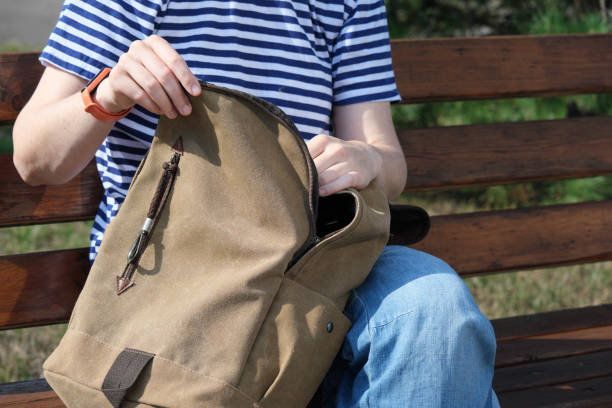 istock Woman is sitting on park bench and looking for something in her backpack 1333167714