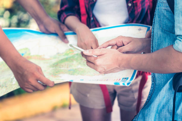 istock Tourists group holding a map and searching direction on location map and using smartphone GPS technology for street searching locations. 1333168590