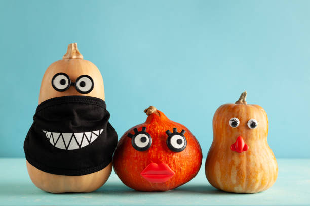 istock Funny pumpkins with faces and in a black protective mask on pastel blue background. 1333170241