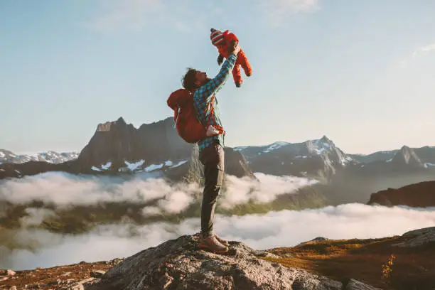 Photo of Father holding up baby hiking in mountains family fun travel vacation with child active healthy lifestyle man and infant outdoor Fathers day holiday