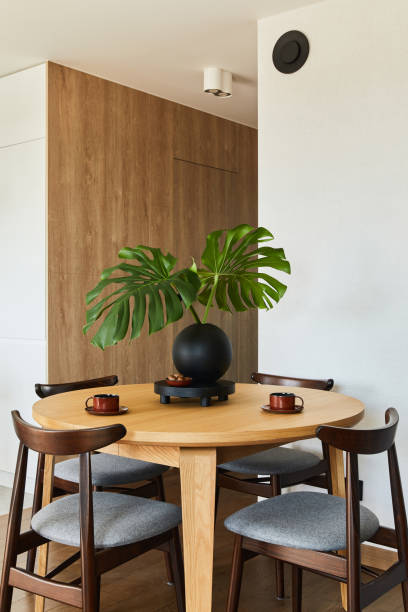 istock Stylish dining space interior design with rounded dining table. Creative walls with wooden panels. Minimalistic style an plant love concept. 1333170558