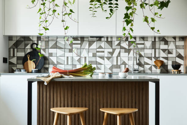 istock Stylish kitchen interior design with dining space. Workspace and kitchen island with kitchen accessories on the back ground. Creative walls with wooden panels. Minimalistic style an plant love concept. 1333170565