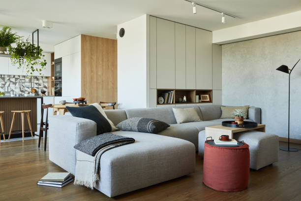 istock Stylish living room interior design with dining space, kitchen island, grey sofa. Workspace with kitchen accessories on the back ground. Creative walls with wooden panels. Minimalistic style an plant love concept. 1333170587