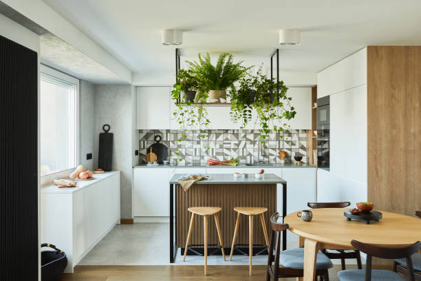 istock Stylish kitchen interior design with dining space. Workspace with kitchen accessories on the back ground. Creative walls with wooden panels. Minimalistic style an plant love concept. 1333170629