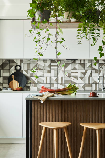 istock Stylish kitchen interior design with dining space. Workspace and kitchen island with kitchen accessories on the back ground. Creative walls with wooden panels. Minimalistic style an plant love concept. 1333170646