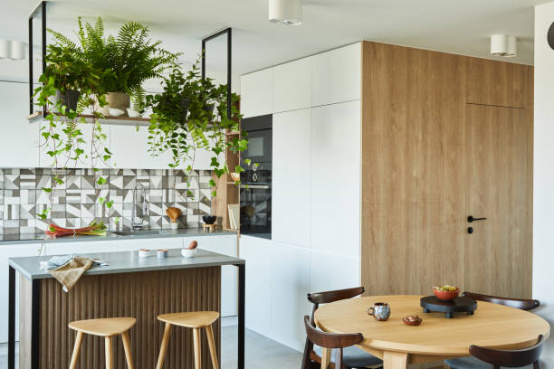 istock Stylish kitchen interior design with dining space. Workspace with kitchen accessories on the back ground. Creative walls with wooden panels. Minimalistic style an plant love concept. 1333170670