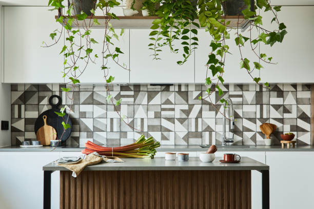 istock Stylish kitchen interior design with dining space. Workspace and kitchen island with kitchen accessories on the back ground. Creative walls with wooden panels. Minimalistic style an plant love concept. 1333170690