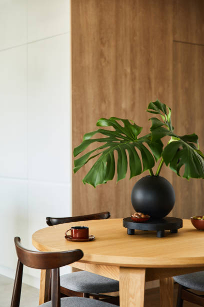 istock Stylish dining space interior design with rounded dining table. Creative walls with wooden panels. Minimalistic style an plant love concept. 1333170693