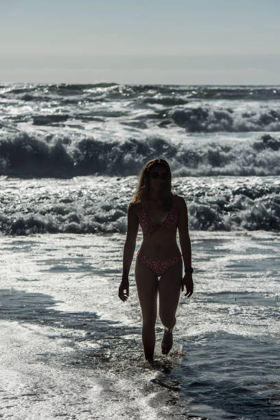 istock pretty young woman walking alone along the beach 1333173261