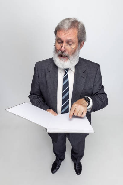 istock High angle view of elderly gray-headed man, professor, teacher posing isolated on gray studio background. Concept of professional occupation, job, education and motivation. 1333175271