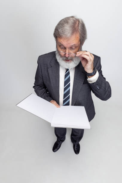 istock High angle view of elderly gray-headed man, professor, teacher posing isolated on gray studio background. Concept of professional occupation, job, education and motivation. 1333175281