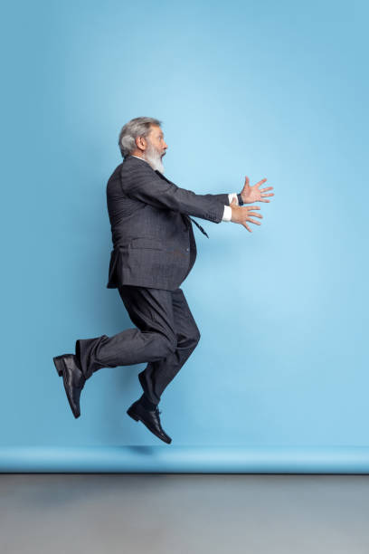 istock Scared professor, teacher, gray-headed bearded man running, hurrying to class isolated on blue studio background. Funny meme emotions 1333175301
