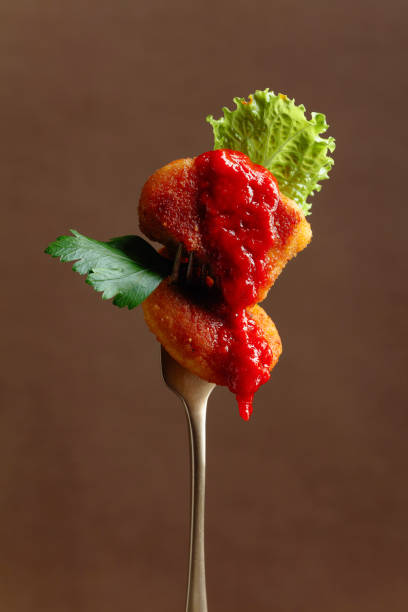 istock Fried chicken nuggets with ketchup, parsley and salad on a fork. 1333180151