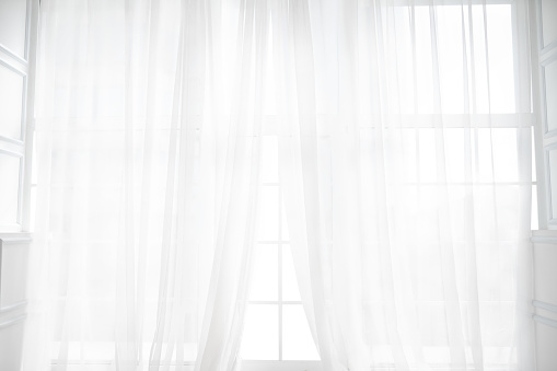 Backlit window with white curtains in empty room. Abstract interior