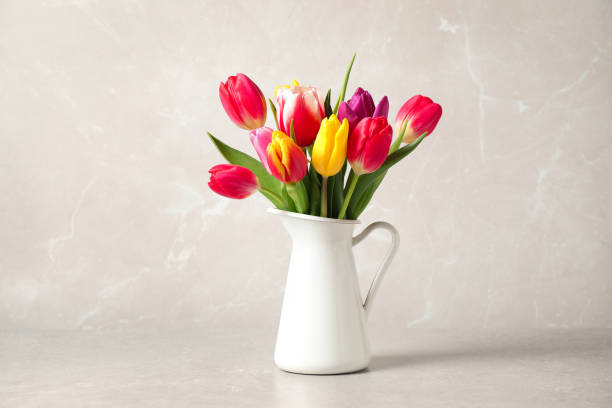 istock Beautiful spring tulips in vase on table against light marble background 1333185525