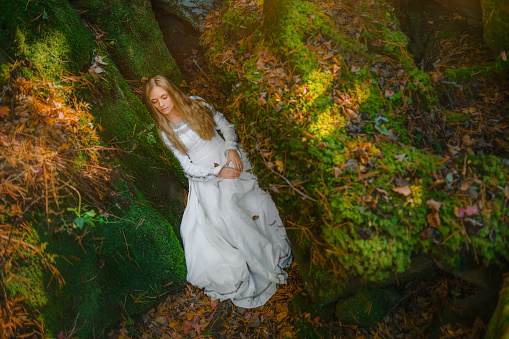 Beautiful young woman in a white dress walk in the middle of a forest